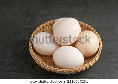 Fresh chicken eggs ( Telur Ayam Kampung ). White eggs served in bamboo plate with copy space. Selective focus image.
