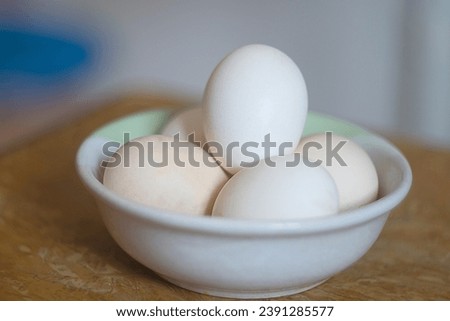 Fresh chicken eggs ( Telur Ayam Kampung ). White eggs served in white bowl on wooden table. Selective focus image.