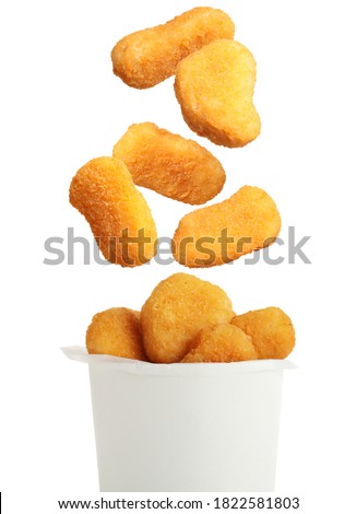 Fresh chicken nuggets falling into container on white background