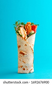 Fresh chicken roll with fresh tomatos, salad, cheese and onions isolated on bright blue background. Side view.