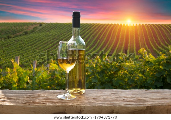 A fresh chilled glass of ice wine\
overlooking a Canadian vineyard during a Summer\
sunset