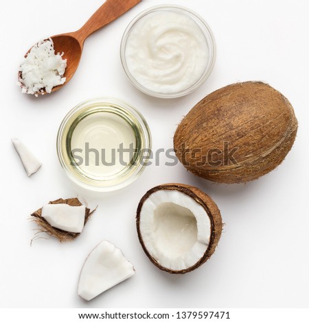 Fresh chopped coconuts, coco flesh and bowls of coconut oil on white background, top view. Coconut body care concept
