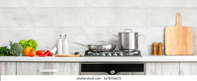Fresh clean vegetables being put on a kitchen desk top, ready for cooking, front view of modern kitchen countertop with domestic culinary utensils on it, home healthy cooking concept banner