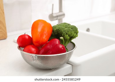 Fresh clean vegetables in colander on countertop near sink. Space for text - Powered by Shutterstock