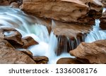 Fresh and clean water cascading off of sandstone rocks into a slot canyon with a blue tint visible in the water. Silky water effect.