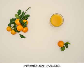 Fresh Clementines - Citrus Clementina - With Green Leaves And Fresh Juice On Beige Background. Hybrid Of Small-sized Tangerines. Overhead, Copy Space