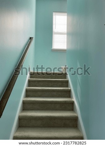 A fresh coat of interior wall paint going up a flight of stairs. The light blue or teal color also has a slight sheen, or a satin finish.