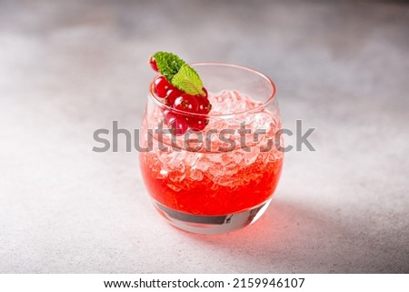 Fresh cocktail with crushed ice, red currant and mint on gray background. Summer cold drink concept with copy space