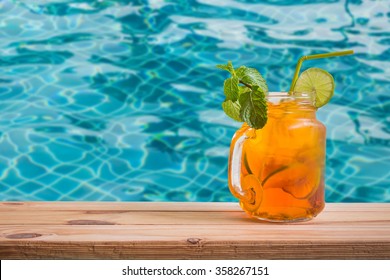 Fresh cocktail with lemon tea on wooden table over swimming pool background - Powered by Shutterstock