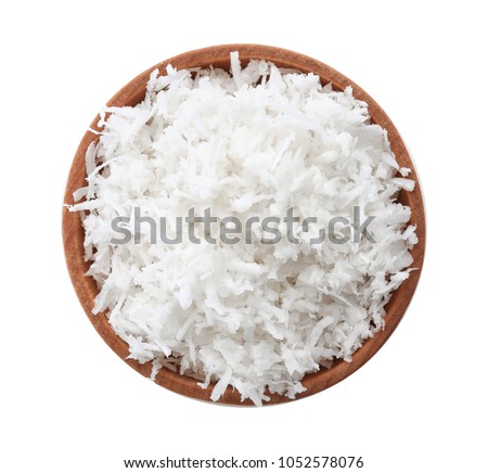 Fresh coconut flakes in bowl on white background, top view