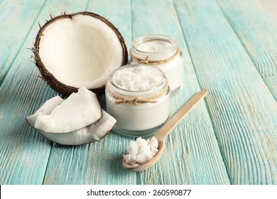Fresh coconut oil in glassware and wooden spoon on color wooden table background - Shutterstock ID 260590877