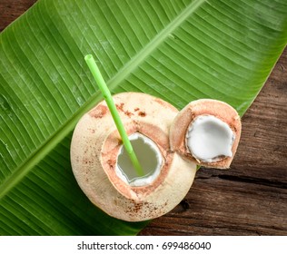 Fresh Coconut Ready To Serve As Beverage. Young Coconut Fruit Cut Open To Drink Juice And Eat. Flat Lay On Green Banana Leaf And Wood Background.