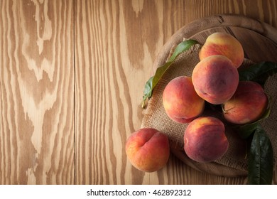 Fresh, cold peach tea with mint, ice cubes and peaches fruits on wooden background.