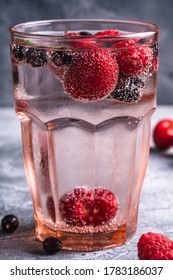 Fresh Cold Sparkling Water Drink With Cherry, Raspberry And Currant Berries In Red Faceted Glass On Stone Concrete Background, Summer Diet Beverage, Angle View Macro