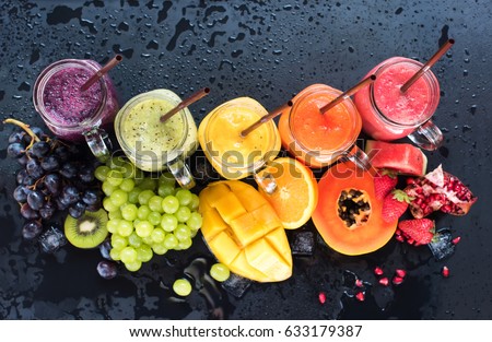 Fresh Color Juices Smoothie Violet Green Yellow Orange Red from Tropical Fruits Kiwi Water Melon Strawberry Apple Orange Banana Pine Apple Bottles multi-colour rainbow Dark Background