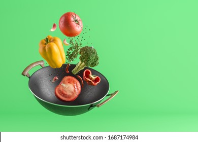 Fresh Colored Vegetables Flying From The Wok. Green Studio Background