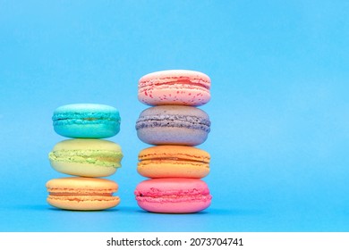 Fresh Colorful Macarons Stacked Into Two Pyramides  On The Blue Background.  Isolated French Sweet Macaroons. Side View. Text Place.