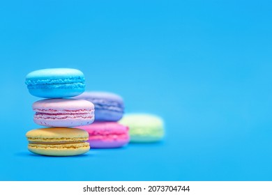 Fresh Colorful Macarons Stacked Into Three Pyramides  On The Blue Background.  Isolated French Sweet Macaroons. Side View. Text Place.