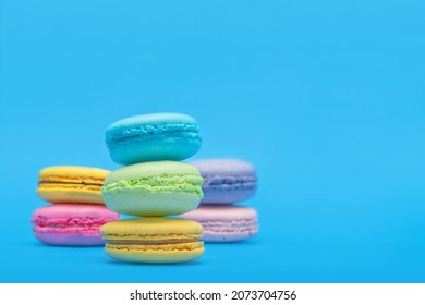 Fresh Colorful Macarons Stacked Into Three Pyramides  On The Blue Background.  Isolated French Sweet Macaroons. Side View. Text Place.