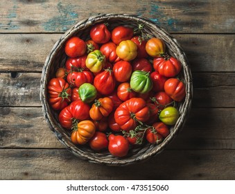 Fresh colorful ripe Fall heirloom tomatoes in basket over wooden background, top view, horizontal composition - Powered by Shutterstock