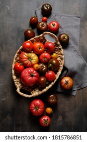 Fresh Colorful Ripe Fall Or Summer Heirloom Variety Tomatoes In A Basket Over Dark Wooden Table Background. Local Market Seasonal Produce