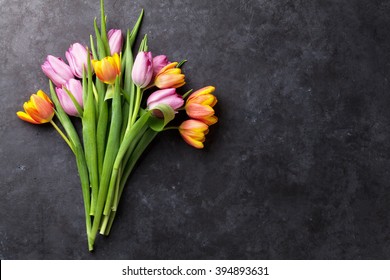 Fresh colorful tulip flowers on dark stone table. Top view with copy space