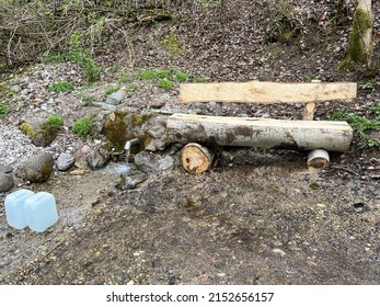 A Fresh And Cool Spring Comes Out Of The Ground. Cool And Delicious Spring Water. Natural Groundwater Source With Copyspace. Bench For Rest