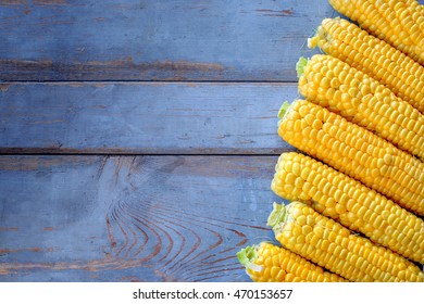 Fresh corn on cobs on rustic wooden table. Rustic wooden background