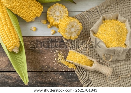Fresh corn on cobs on rustic wooden table, top view. Dark wooden background freshly harvested organic corn. Corn grits in cloth sack.