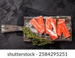 Fresh Crab sticks, crabmeat on wooden board. black background. top view.