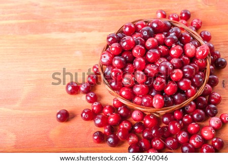 Fresh cranberries in a small basket on a wooden background