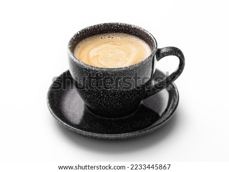 Fresh creamy black coffee in black cup with saucer on white.