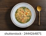 Fresh creamy salmon fish soup with potatoes, carrots, broccoli, peppers and onions in a ceramic plate on a wooden table, close up, top view. A delicious dinner consists of fish soup with salmon