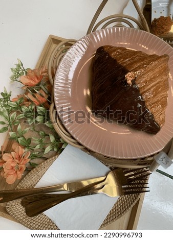fresh croissant with chocolate placed on a beautiful plate and decorated with artificial orange flowers.