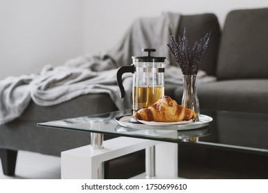 Fresh croissant and french press pot with brewed herbal tea and vase with dried lavender on glass coffee table in living room. Breakfast concept - Powered by Shutterstock