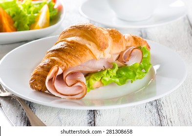 Fresh croissant with ham and salad leaf with sfresh salad on white
