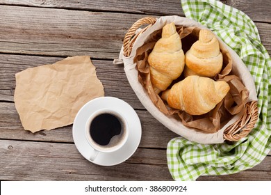 Fresh Croissants, Coffee And Piece Of Paper On Wooden Table. Top View With Copy Space