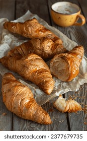 Fresh croissants with a cup of cappuccino (coffee) on a wooden background. Popular tasty breakfast. - Shutterstock ID 2377679735