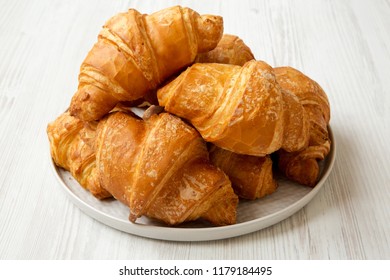 Fresh Croissants On Grey Round Plate On White Wooden Table, Side View. 