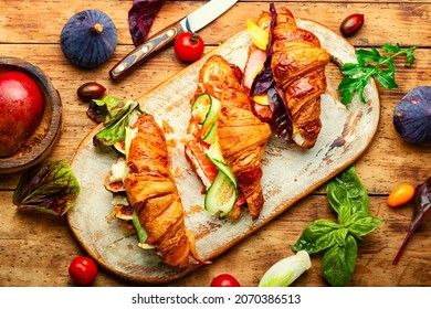 Fresh croissants,healthy breakfast on the kitchen board.Croissants with trout, meat bacon, vegetables and fruits