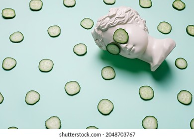 Fresh Cucumber Slices Pattern And Ancient Bust With A Cucumber Slice Mask On Eyes On Green Background. Creative Beauty Concept. Spa Beauty Treatments At Home, Body Care Concept, Organic Cosmetics.