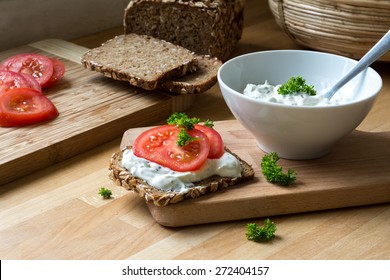 Fresh Curd Cheese Dip With Herbs In A White Bowl And Rustic Wholegrain Bread With Tomatoes On A Kitchen Board, Healthy And Powerful Meal With Natural Food Products