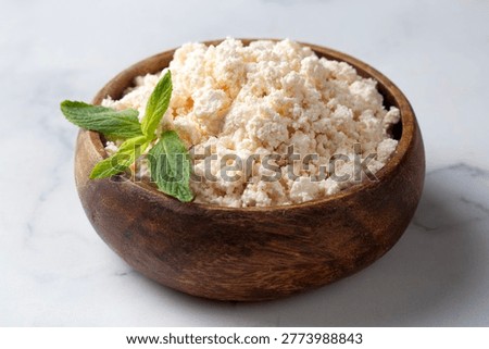 Fresh curd cheese (lor cheese) in a rustic wooden bowl garnished with mint leaves
