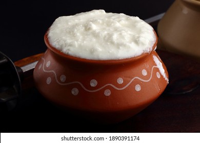 Fresh curd in traditional curd pot on dark wooden background 