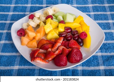 Fresh Cut Fruit On A White Plate With Strawberries, Mango, Pineapple, Grapes, Bananas, And Melon