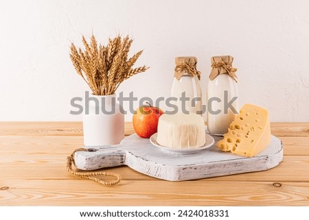 A fresh dairy products cheese, milk, apples and ears of corn in a vase for the holiday of Jewish Shavuot. Front view