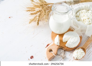 Fresh dairy products (milk, cottage cheese), wheat, white wood background, top view