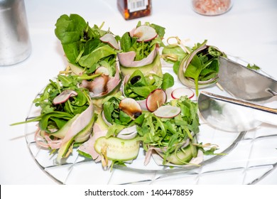 Fresh Dark Leafy Greens Salad Lettuce Mix With Cucumbers, Rucola, Radishes Dressing On A Plate During Breakfast Buffet Or Brunch Catering Event, Food Pliers On The Plate. Vegetarian And Vegan Dish