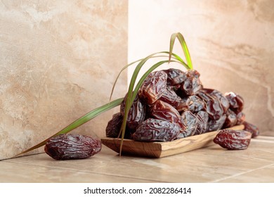 Fresh Dates Fruit In A Wooden Dish On A Beige Ceramic Table.