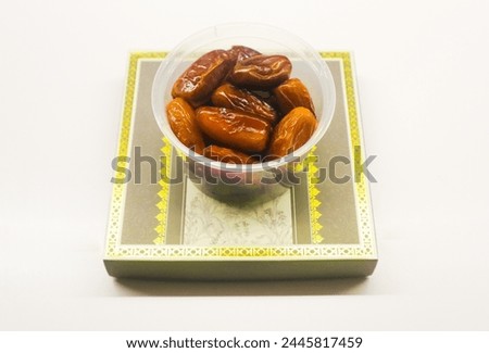 Fresh dates in a plastic bowl on white isolated background.